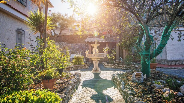 A courtyard with a central fountain, surrounded by potted plants and a stone wall. - Villa Fuji Sierra de la Pandera (AN)