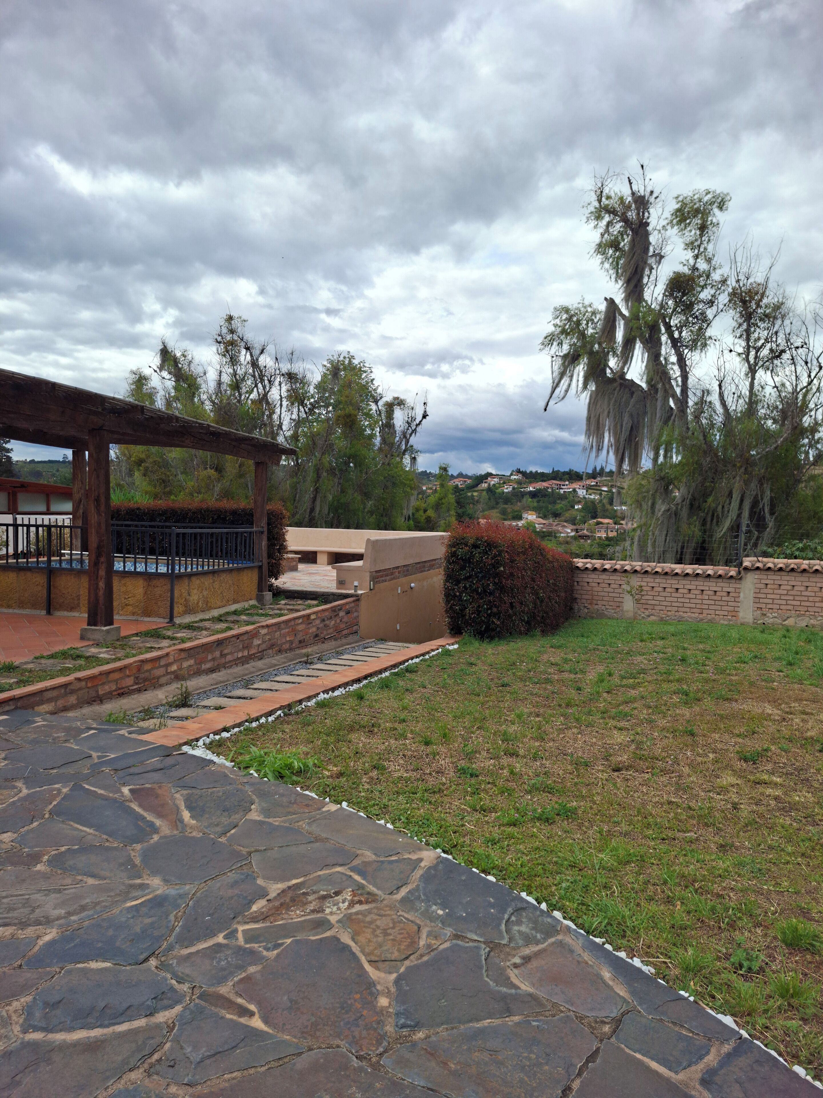 Un camino de piedra conduce a un porche cubierto con un muro de ladrillo y vistas a un barrio residencial.