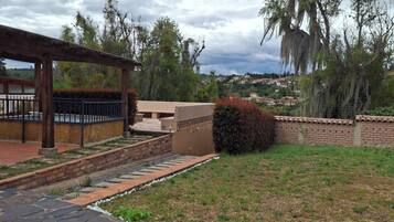 Un camino de piedra conduce a un porche cubierto con un muro de ladrillo y vistas a un barrio residencial.