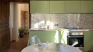 A kitchen with green walls, a white countertop, and a dining table with chairs. - La Leccina - Dependance (San Gimignano)