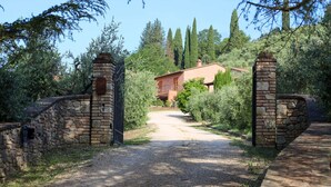 A gravel driveway leading to a rustic house with stone walls and a metal gate. - La Leccina - Dependance (San Gimignano)