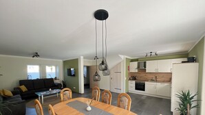 A modern living space with a dining area, kitchen, and a living room. - Gemütliche Ferienwohnung mit Blick auf Wald Wiesen und Dolomiten (Gerolstein)