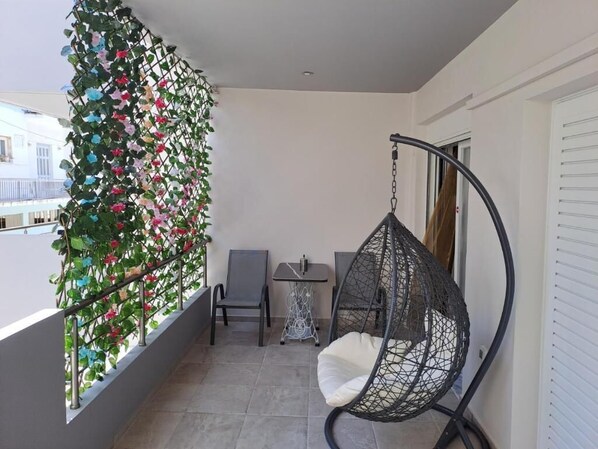 A balcony with a hanging chair, a small table, and a chair. - Μodern apartment in Nafplio (Nafplio)