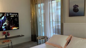 Ein Hotelzimmer mit Bett, Fernseher, Heizkörper, einem Fenster mit Vorhängen und einem Bild an der Wand.