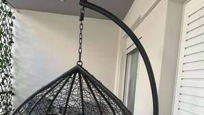 Ein schwarzer Hängekorbstuhl mit weißen Kissen in einem Raum mit weißen Wänden und einem Fenster.