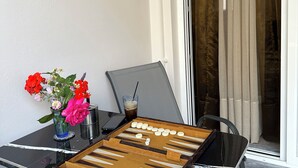 Ein Tisch mit Schachbrett, einer Blumenvase und einem Glas Eistee.