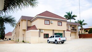 A two-story building with a beige facade and a red roof. There is a white pickup truck parked in front. - Fox Premium Hotel Jos  (Jos)