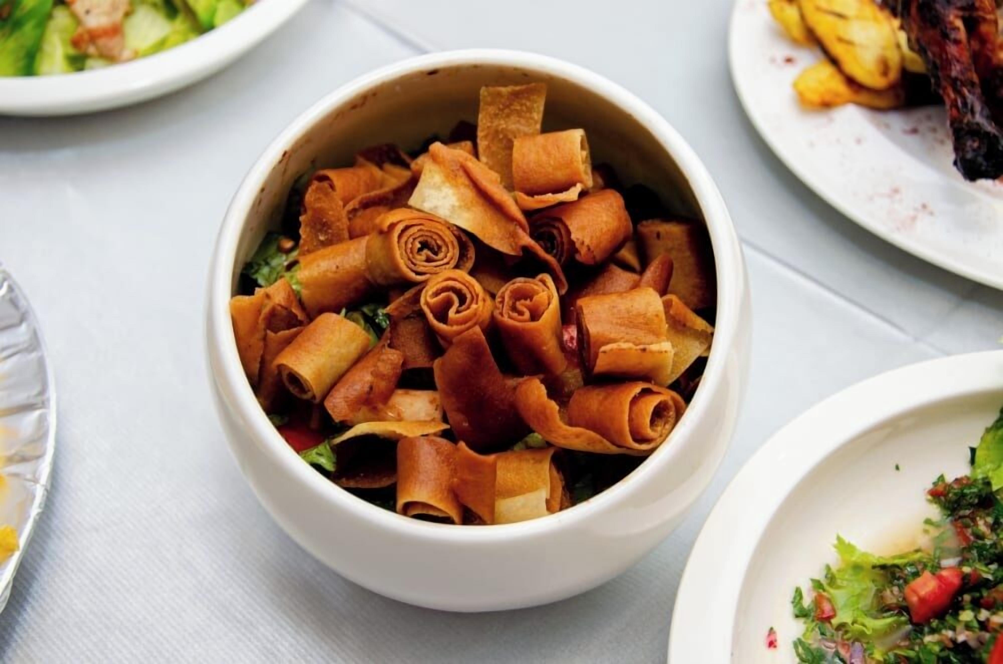 A bowl of rolled spring rolls with a side salad.