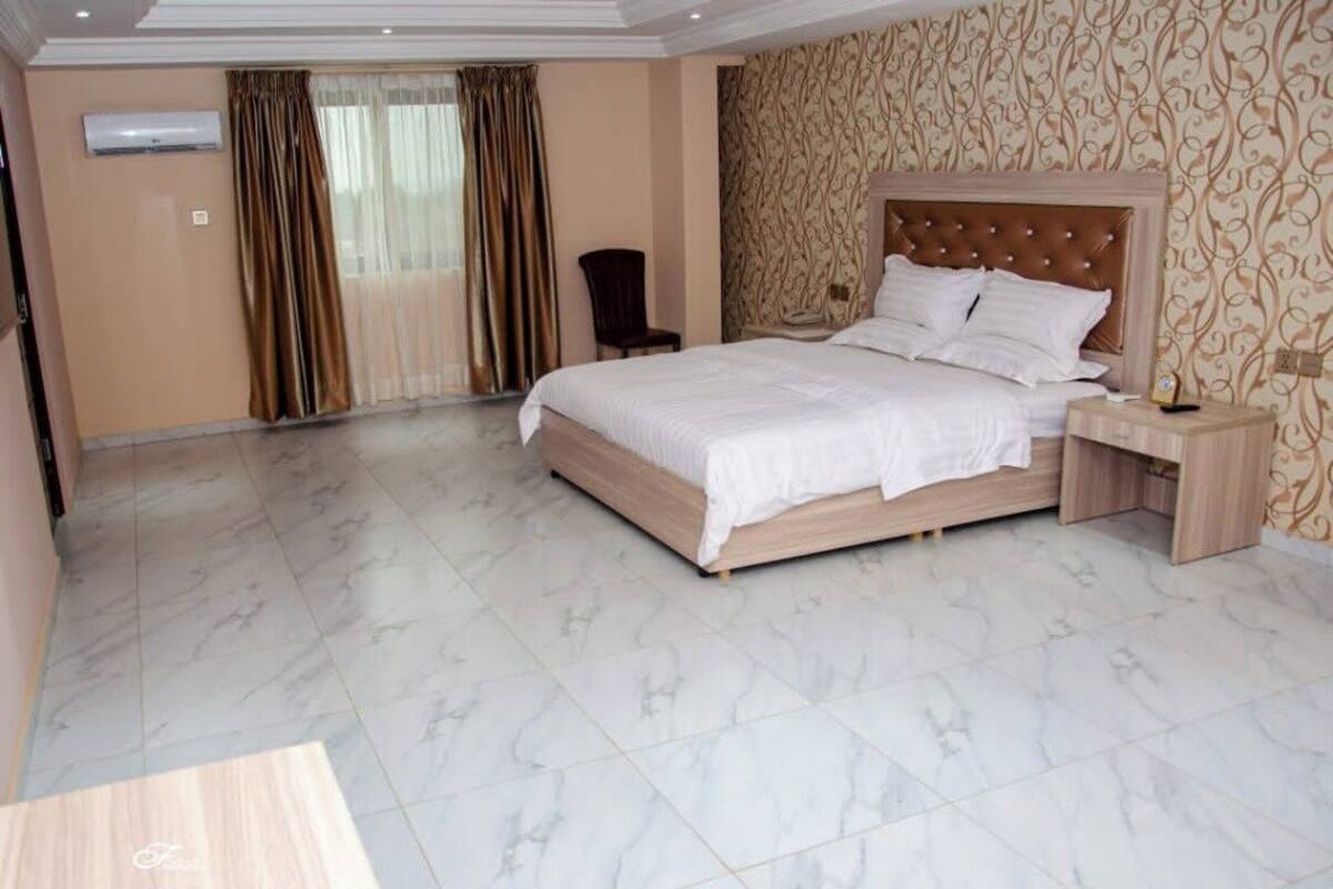 A spacious bedroom with a large bed, a nightstand, and a chair.