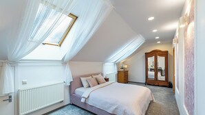 Ein Schlafzimmer mit Schräge, einem großen Bett, einem Kleiderschrank und einer Heizung.