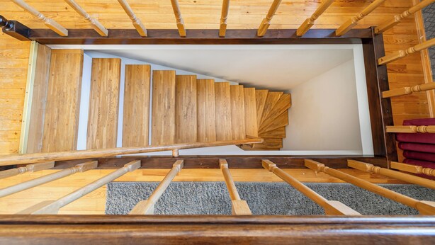 Eine gerade Holztreppe mit einer Teppich-Ausstattung auf dem Podest.
