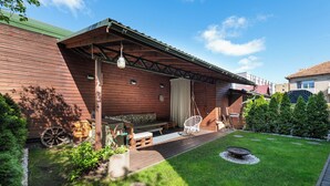 Eine Holzhütte mit Veranda, Sitzgelegenheiten im Freien und einer Feuerstelle.