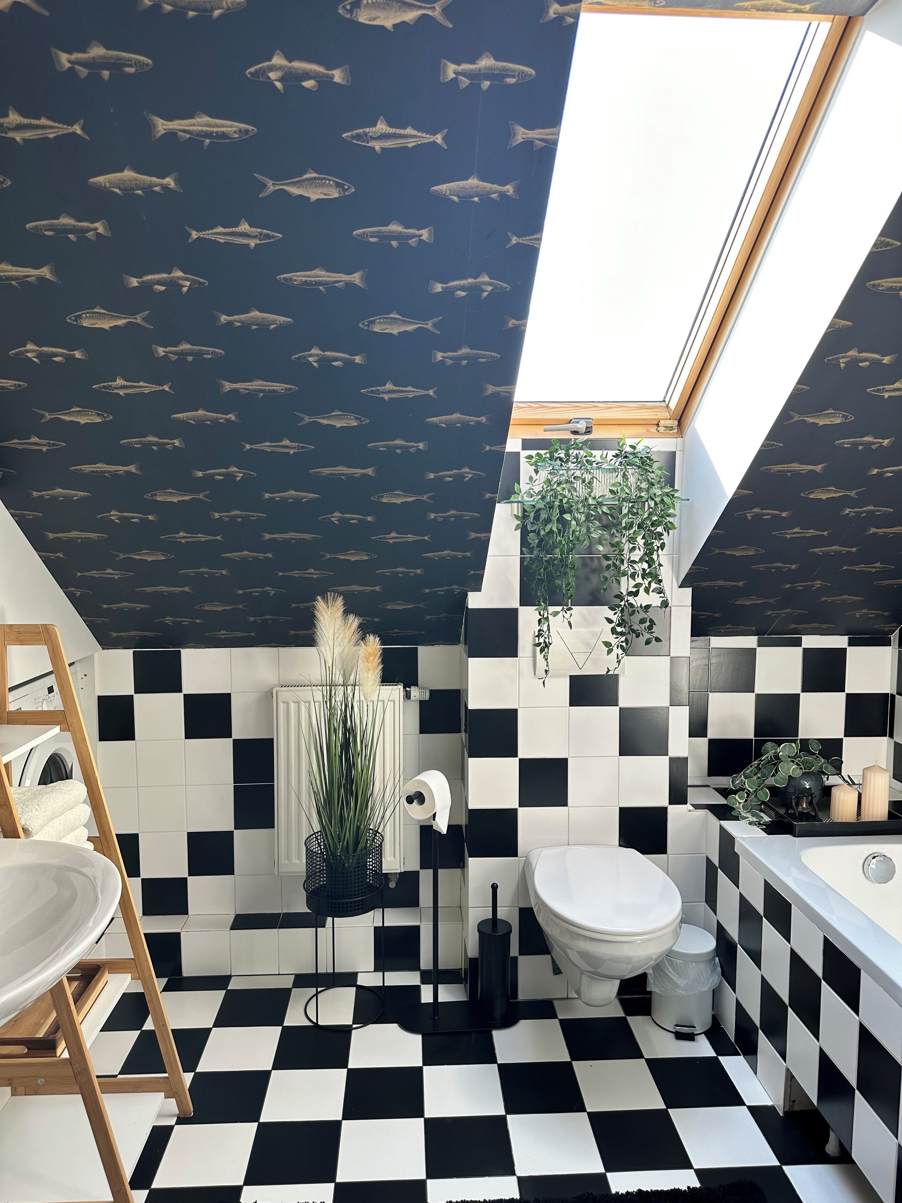 Een badkamer met zwart-wit geruite tegels, een toilet, een wastafel en een douchehoek.