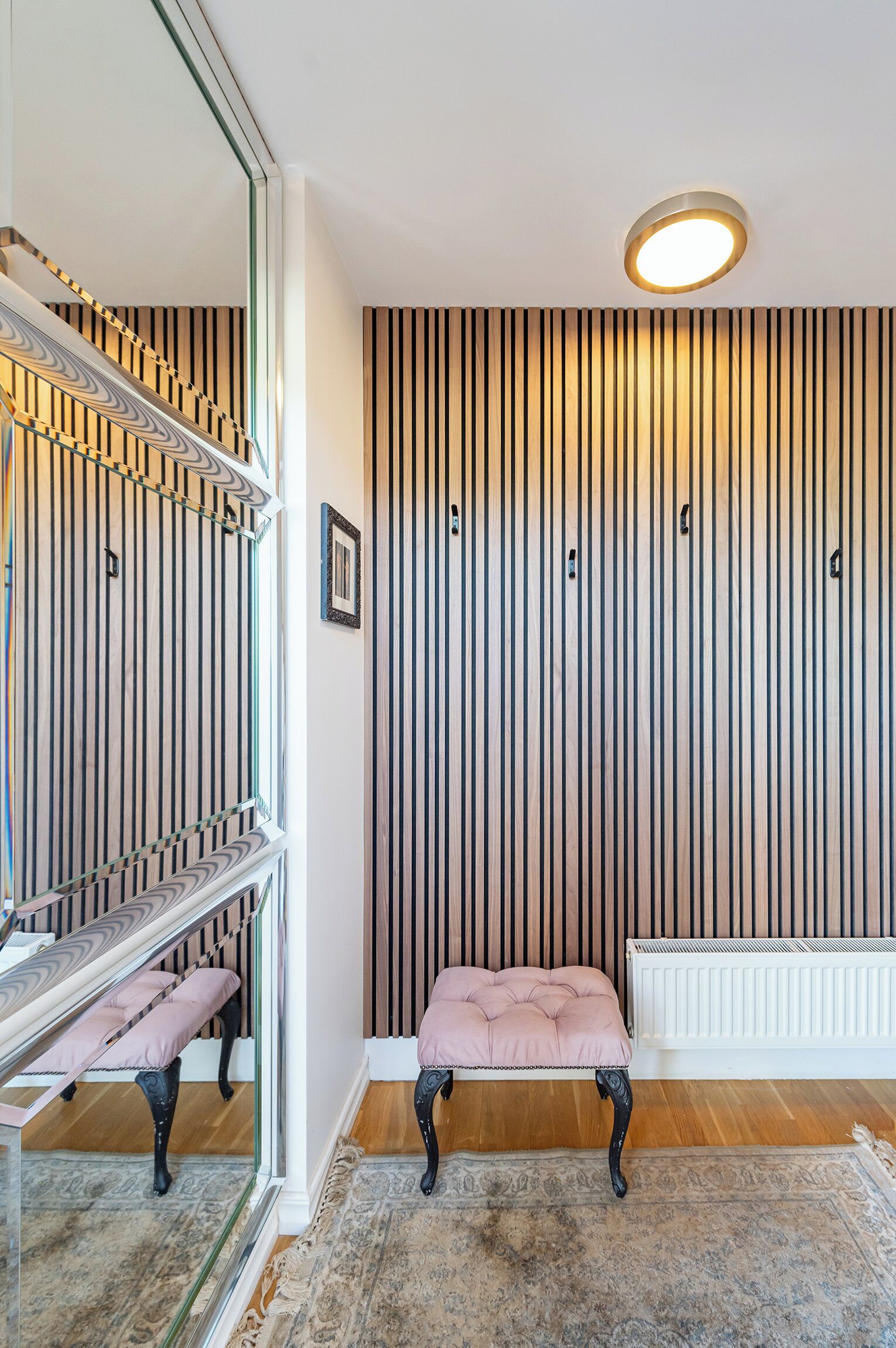 Un interior moderno con una escalera, un banco, un radiador y una pared a rayas.