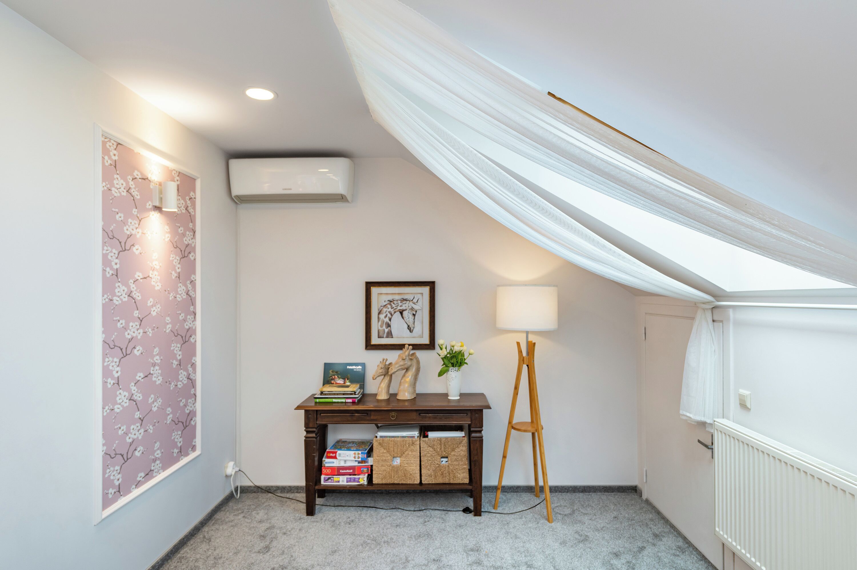 A corner room with a desk, a lamp, a framed picture, and a radiator.