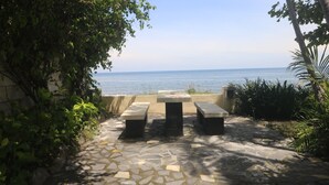 An outdoor seating area with stone flooring and a view of the sea.