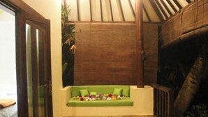 A room with a green sofa adorned with flowers, a wooden ceiling, and a large plant.