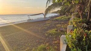 A beach with boats, a wooden structure, and lush greenery.