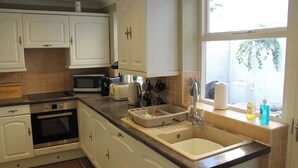 A kitchen with white cabinets, a microwave, a toaster, and a sink. - Rockton House (Whitby)