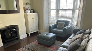 A living room with a fireplace, a sofa, an ottoman, and a patterned rug. - Rockton House (Whitby)