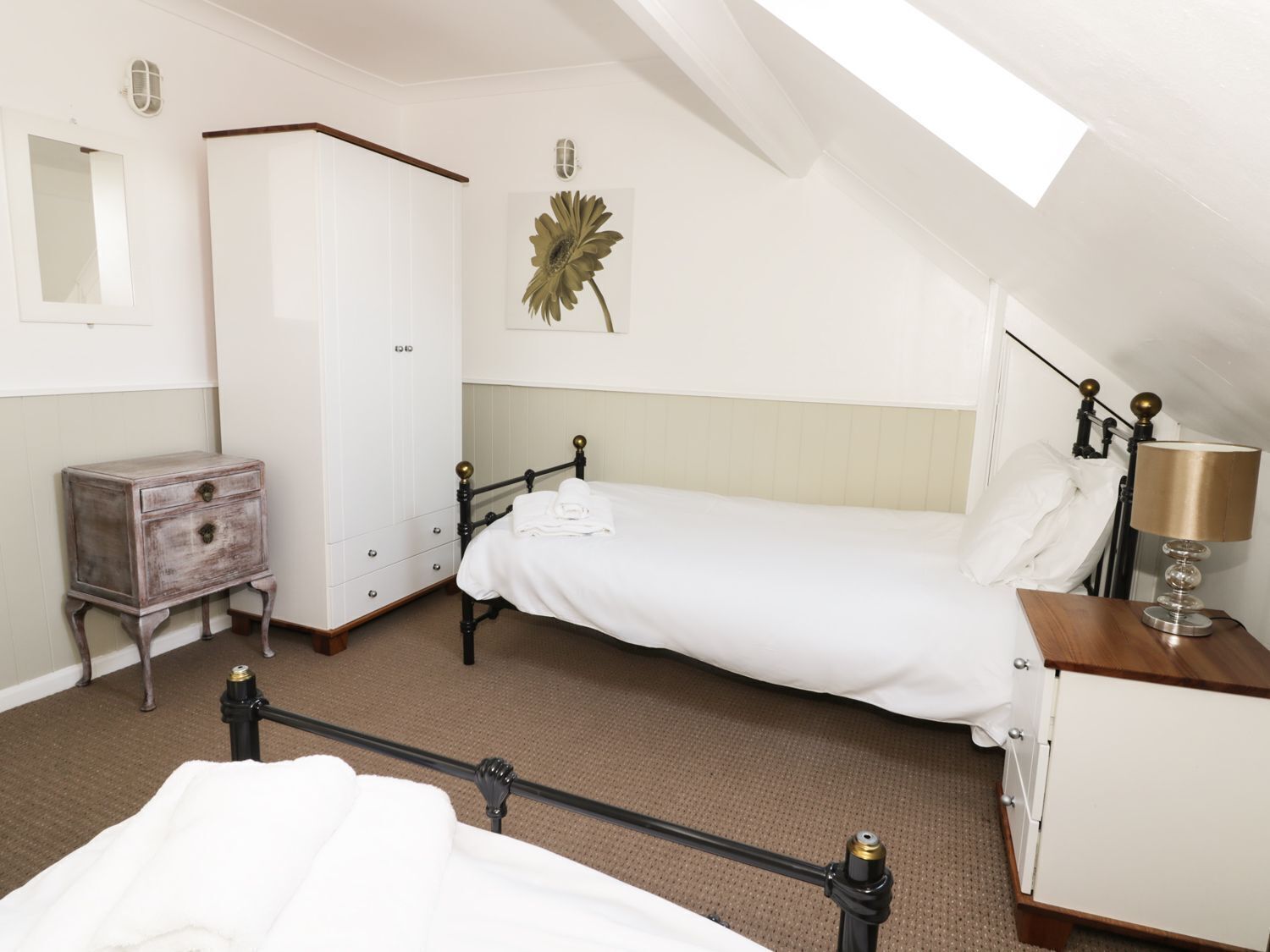 A bedroom with a single bed, a wardrobe, a nightstand, and a lamp.