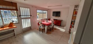 Un'area pranzo con tavolo e sedie, una TV a parete e una libreria.