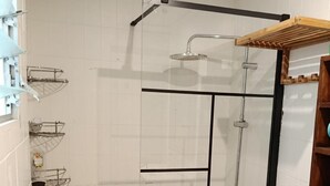 Ein Duschbereich mit Glasabtrennung, einer Handbrause und einer Handbrause mit Schlauch.