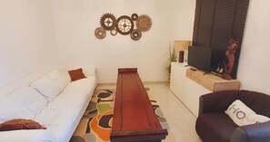 A living room with a sofa, a coffee table, a TV, and decorative wall art.