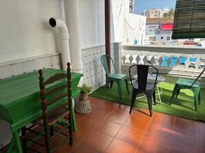 A terrace with a green table, chairs, and a potted plant.