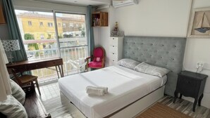 Ein Hotelzimmer mit Bett, Schreibtisch, Stuhl, Nachttisch und Blick ins Freie.