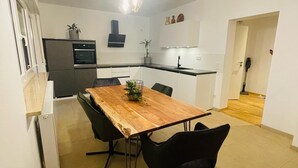 Une cuisine moderne avec une table à manger en bois, des chaises noires et des luminaires suspendus.