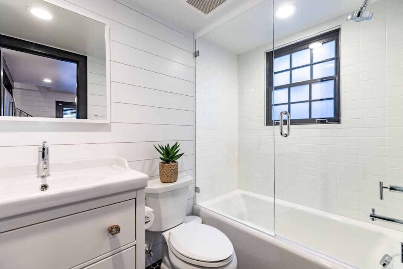 A modern bathroom with a white sink, toilet, and bathtub.