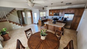 Cocina amplia con armarios de madera, una isla central y un comedor con una mesa redonda y sillas.