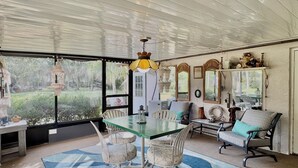 A spacious room with a large dining table, comfortable seating, and a view of a lush garden. - Peaceful house right on the spring. Great place to get away from everything. (Spring Hill)