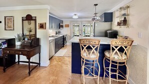 A kitchen with dark cabinets, a central island, and two wicker bar stools. - Peaceful house right on the spring. Great place to get away from everything. (Spring Hill)