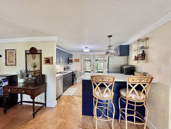 A kitchen with dark cabinets, a central island, and two wicker bar stools. - Peaceful house right on the spring. Great place to get away from everything. (Spring Hill)