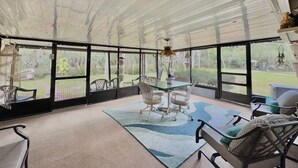 A covered patio with a table and chairs, a patterned rug, and a view of a garden. - Peaceful house right on the spring. Great place to get away from everything. (Spring Hill)