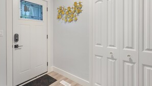 A hallway with a white door, a blue-framed window, and a wall-mounted yellow geometric decoration. - Urban Nest 7 mins from Edmonton downtown <br> (Edmonton)