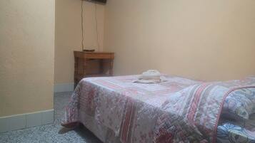 Un dormitorio con una cama, una mesita de noche de madera y una lámpara colgante.