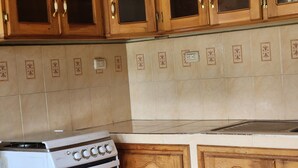 A kitchen with wooden cabinets, a white stove, and patterned tiles on the wall. - Hostal Sweet Dreams (Panajachel)