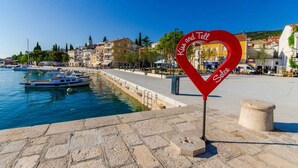 A waterfront promenade with a red heart-shaped sign reading "Kiss and Tell Solce." - Holiday apartment with internet access (Selce)