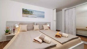 A modern hotel room with a large bed, a nightstand with a lamp, a painting of a beach, and a sliding door closet. - Holiday apartment with internet access (Selce)
