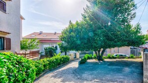 A residential area with a paved driveway, a large tree, and houses with red-tiled roofs. - Holiday apartment with internet access (Selce)