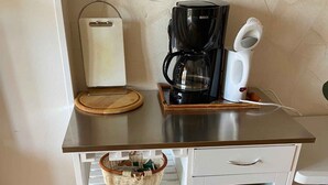 Eine Küchenzeile mit Kaffeemaschine, Toaster und einem Schrank mit Körben und Geschirr.