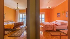 Une chambre avec deux lits, un lustre et une vue sur l’extérieur, visible à travers une porte vitrée.