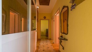 Un couloir avec un tapis à motifs, une porte en bois au fond et un miroir fixé au mur.
