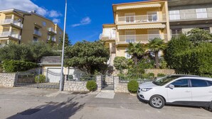 Un immeuble résidentiel doté de nombreux balcons, d’une entrée sécurisée et d’une voiture garée.