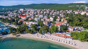 Eine Luftaufnahme einer Küstenstadt mit Strand, Wohnhäusern und einem Yachthafen.