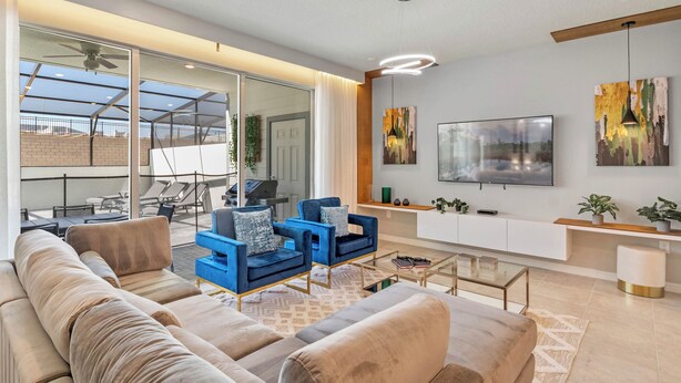 A modern living room with a sofa, armchairs, a coffee table, a TV, and artwork on the wall.