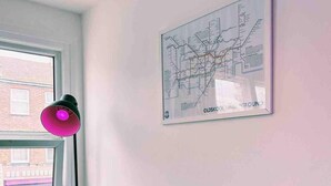 A framed map on a wall with a window and a pink lamp. - London Flat Next to Central Line Tube Station (London)